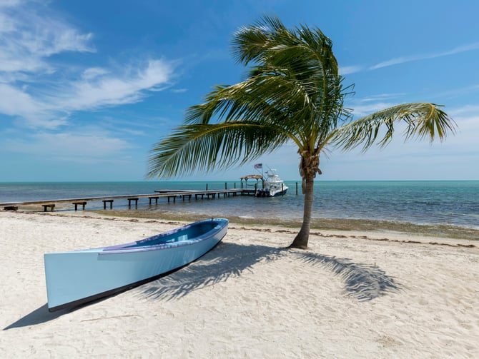 Kayak on a Florida Keys beach with palm tree and dock